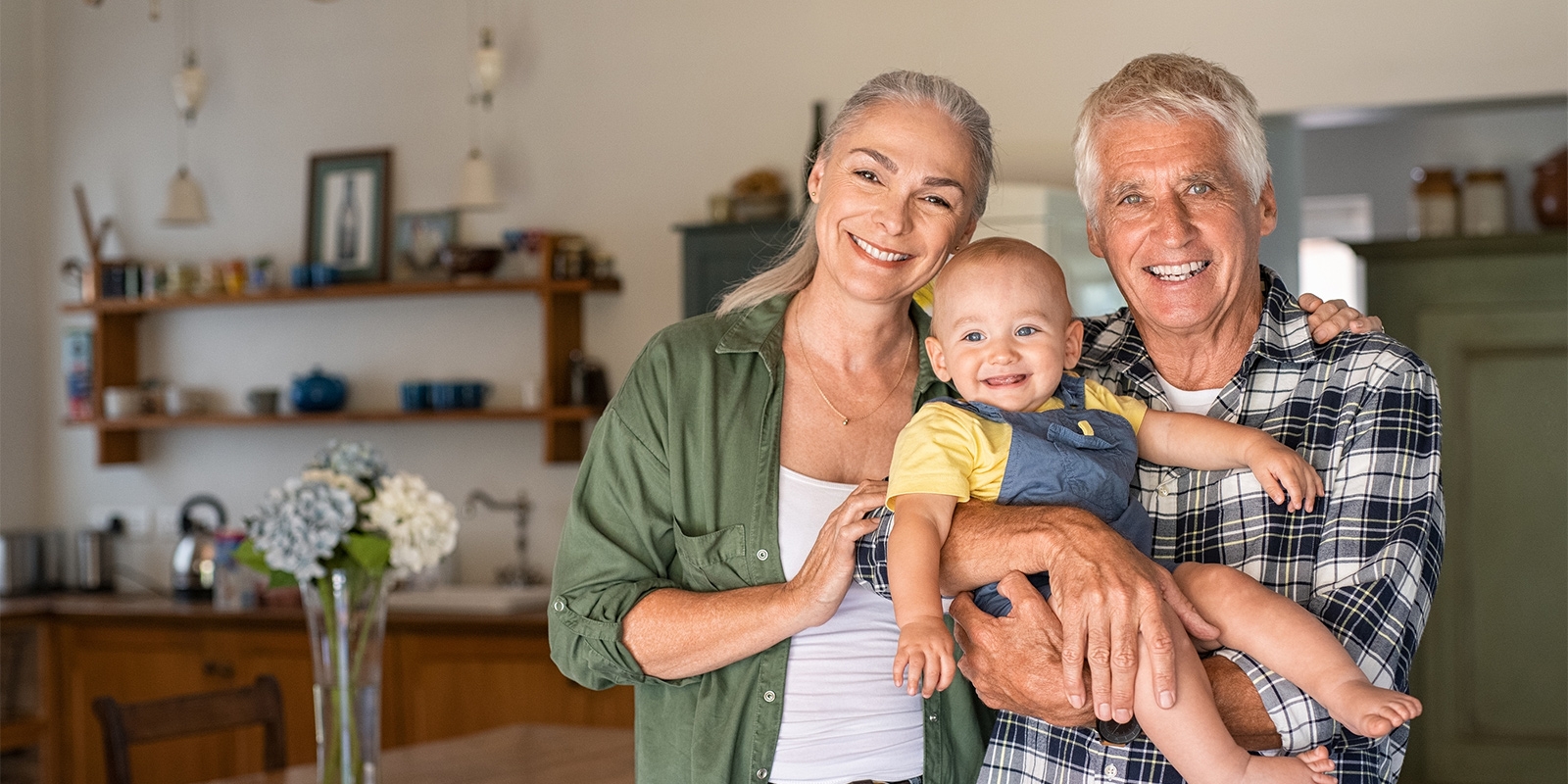 elderly couple smiling and holding a baby