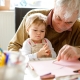 elderly man drawing a picture with a baby
