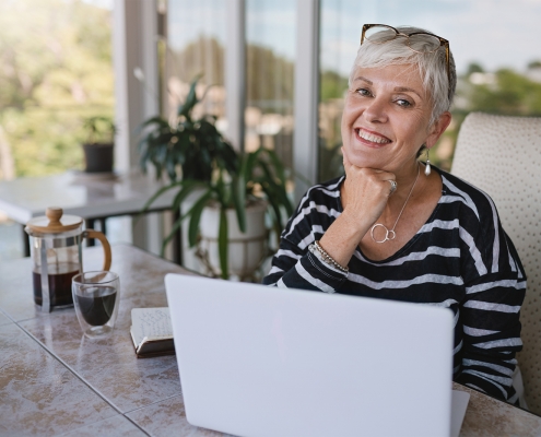 elderly woman smiling while at her laptop